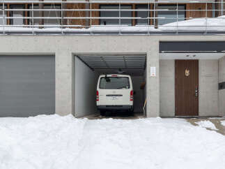 This modern concrete home features a spacious two-car garage with one side offering a secure, enclosed bay for a vehicle.
