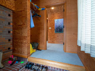 Step into this inviting entryway featuring warm wood paneling and a convenient closet space.