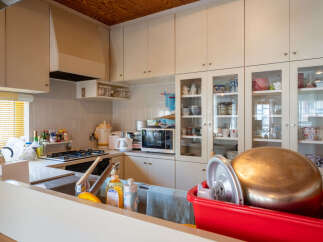 This spacious kitchen features ample cabinet storage, including upper cabinets and glass-front display cabinets, perfect for showcasing dishware.