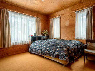 Experience cozy living in this charming bedroom featuring warm wood-paneled walls and ceiling.