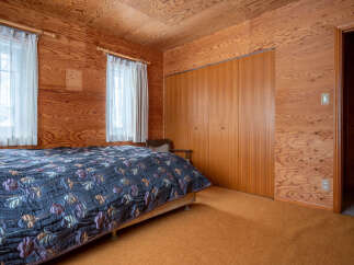This charming bedroom features warm, wood-paneled walls and ceiling, creating a cozy and inviting atmosphere.