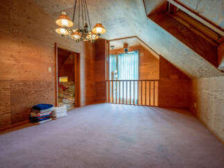 Discover the unique charm of this attic space, featuring warm wood-paneled walls and a cozy carpeted floor.