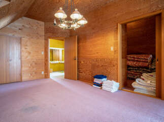Step into a unique bedroom featuring warm wood paneling on the walls and ceiling, creating a cozy and inviting atmosphere.