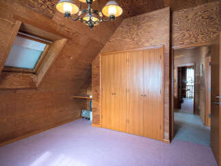 Step into this charming attic room featuring warm wood-paneled walls and a cozy sloped ceiling.