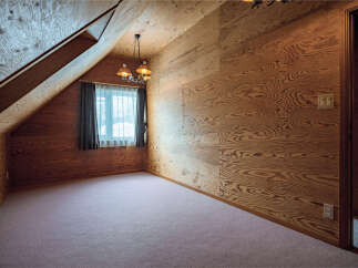 Step into this charming attic room, featuring unique wood-paneled walls and a cozy sloped ceiling.