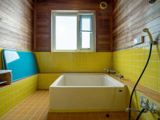 Experience a unique bathing retreat with this charming bathroom featuring vibrant yellow tiled walls and a built-in bathtub.