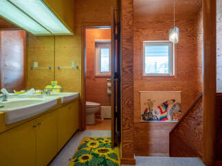 Step into a uniquely designed bathroom featuring a double vanity with bright yellow cabinetry and a large mirror.