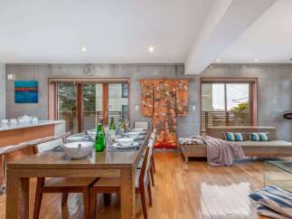 Experience modern living in this spacious open-concept dining and living area, featuring a sleek concrete accent wall and warm hardwood floors.