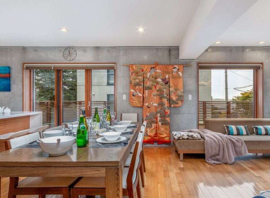 Experience modern living in this spacious open-concept dining and living area, featuring a sleek concrete accent wall and a vibrant Japanese kimono for a touch of cultural elegance.