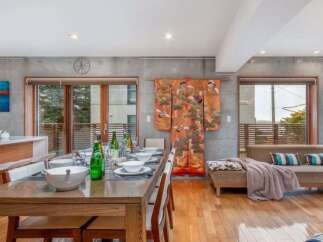 Experience modern living in this spacious open-concept dining and living area, featuring a sleek concrete accent wall and a vibrant Japanese kimono for a touch of cultural elegance.
