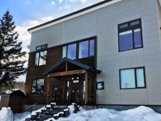 Experience the charm of this winter wonderland property, featuring a modern two-story home with a striking combination of wood and light-colored siding.