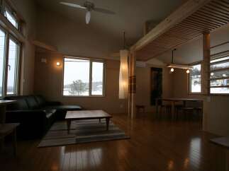 Experience cozy living in this spacious room featuring a large black leather sectional sofa and a wooden coffee table on a striped rug.