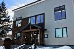 Experience modern living in this stunning multi-story home, featuring a striking contrast between warm wooden siding and sleek, light-colored exterior panels.