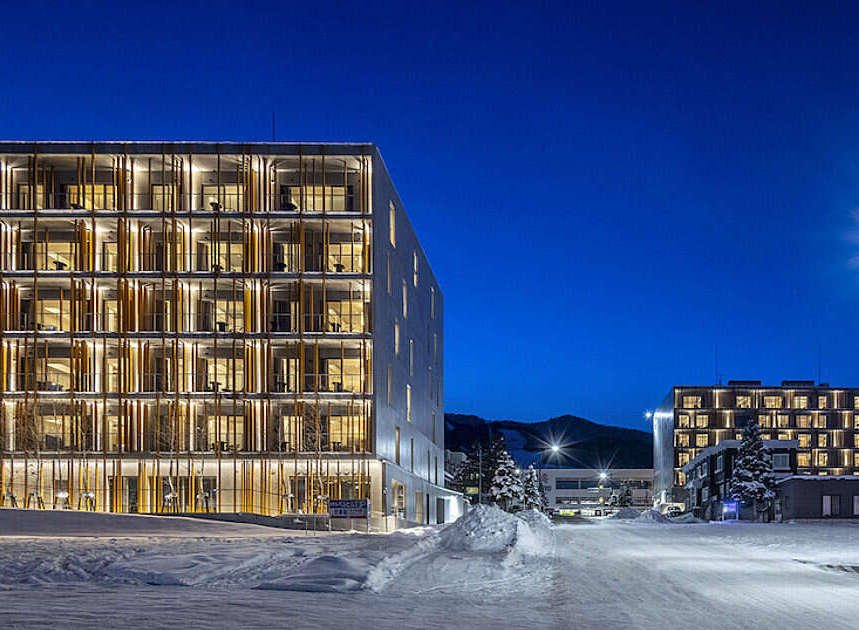 Experience modern living in this stunning multi-story building, featuring a unique facade with vertical wooden elements and abundant natural light through large windows.