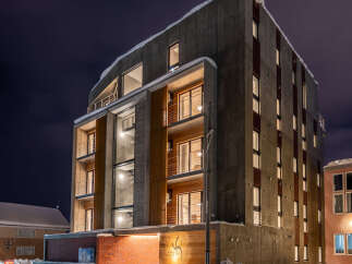 Experience modern living in this striking concrete building, featuring multiple balconies with glass railings and warm wooden accents.