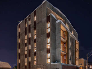 Experience modern living in this striking concrete apartment building, illuminated against the night sky.