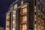 Experience modern living in this striking concrete and wood apartment building, illuminated against the night sky.