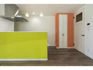 Discover modern living in this stylish apartment featuring a vibrant lime green kitchen island and sleek stainless steel range hood.