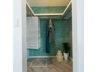 Discover this charming walk-in closet featuring a stylish green floral wallpaper and a convenient hanging rack for your garments.