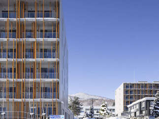 Experience modern living in this multi-story apartment building, featuring a striking facade with vertical wooden accents and glass balconies.