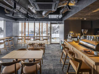Experience the cozy ambiance of this modern cafe, featuring warm wooden furniture and a sleek coffee bar.