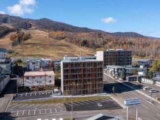 Discover modern living in this multi-story apartment complex, featuring a unique facade with vertical wooden elements and numerous balconies.