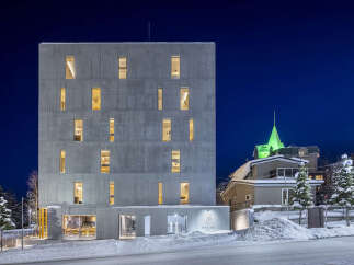 Experience modern luxury in this striking concrete building, illuminated against a deep blue night sky.