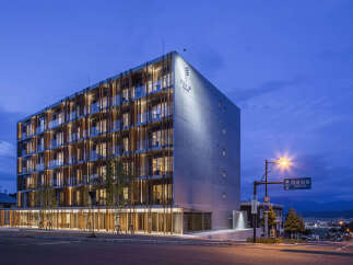 Experience modern luxury at this stunning hotel, featuring a striking architectural design with a concrete facade and warm wooden accents.