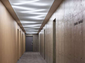 Experience modern elegance in this hotel hallway, featuring a unique wavy ceiling with ambient pink and white lighting.