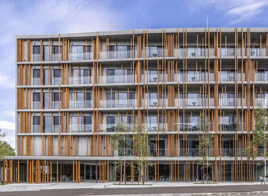 Discover modern living in this stunning multi-story building, featuring a unique facade of concrete and warm wooden vertical slats.