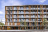 Discover modern living in this stunning multi-story building, featuring a unique facade of concrete and warm wooden vertical slats.