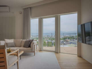 Experience breathtaking panoramic views from this stunning living room, featuring expansive floor-to-ceiling windows that showcase a picturesque cityscape and distant mountains.