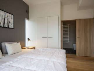 Experience modern comfort in this serene bedroom featuring a plush white duvet and elegant quilted pillows.
