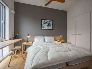 Discover this serene bedroom featuring a comfortable queen-sized bed adorned with crisp white linens and plush pillows.