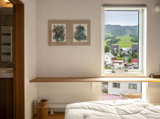 Experience breathtaking mountain views from this charming hotel room, featuring a comfortable bed and a large window overlooking a scenic landscape.