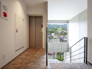 Experience modern living in this stylish apartment building, featuring a convenient elevator and a striking staircase with a scenic mountain view.
