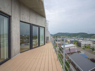 Experience modern living with this stunning property featuring a spacious balcony with panoramic views of the surrounding town and lush green hills.