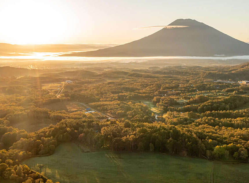 Experience breathtaking sunrise views over a lush, forested landscape, with a majestic mountain peak gracing the horizon.