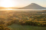 Experience breathtaking sunrise views over a lush, forested landscape, with a majestic mountain peak gracing the horizon.