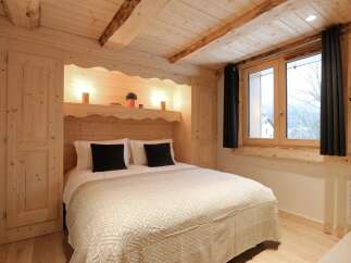Experience cozy mountain living in this charming bedroom featuring a comfortable bed with plush pillows and a decorative throw.