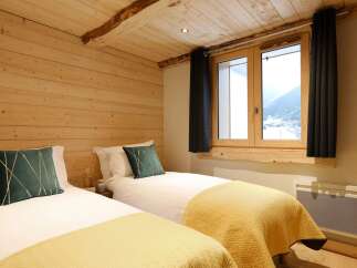 Experience cozy mountain living in this charming bedroom featuring two twin beds, perfect for a comfortable stay.