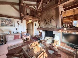 Experience rustic charm in this cozy living room, featuring exposed wooden beams and a grand stone fireplace.