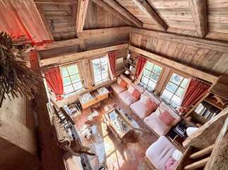 Experience rustic charm in this cozy wooden cabin living room, featuring a plush pink sectional sofa adorned with patterned throw pillows.