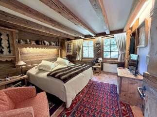 Experience rustic charm in this cozy bedroom, featuring exposed wooden beams and walls that exude warmth and character.