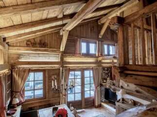 Experience rustic charm in this stunning log cabin interior, featuring exposed wooden beams and a cozy fireplace.