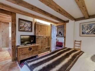 Experience rustic charm in this mountain-view bedroom, featuring exposed wooden beams and a cozy atmosphere.