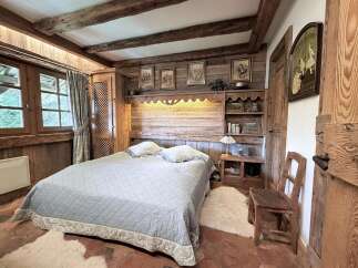 Experience rustic charm in this cozy bedroom featuring exposed wooden beams and a warm, inviting ambiance.