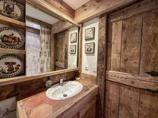 Experience rustic charm in this bathroom featuring a wooden vanity with a terracotta tile countertop and a white ceramic sink.