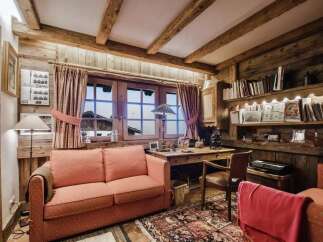 Cozy mountain retreat featuring a rustic living room with exposed wooden beams and a charming fireplace.