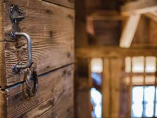 Experience rustic charm with this unique wooden door featuring an antique metal handle and ring.